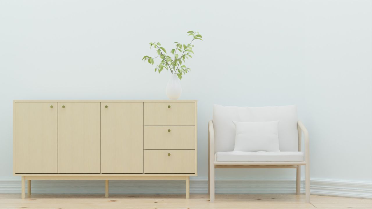 Contact Elegant minimalist interior design featuring a wooden sideboard and armchair with greenery.