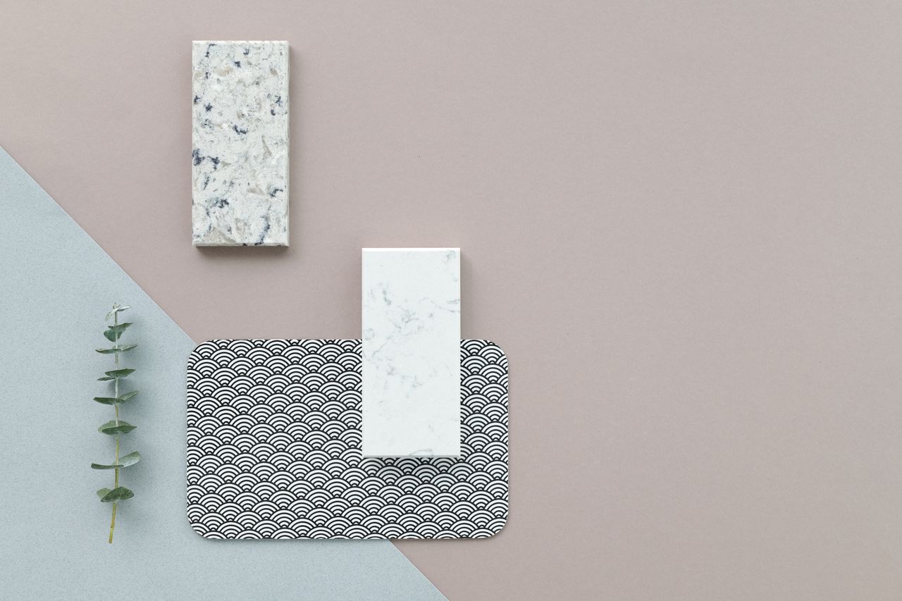 A minimalist flat lay of marble samples and design elements on a textured background.